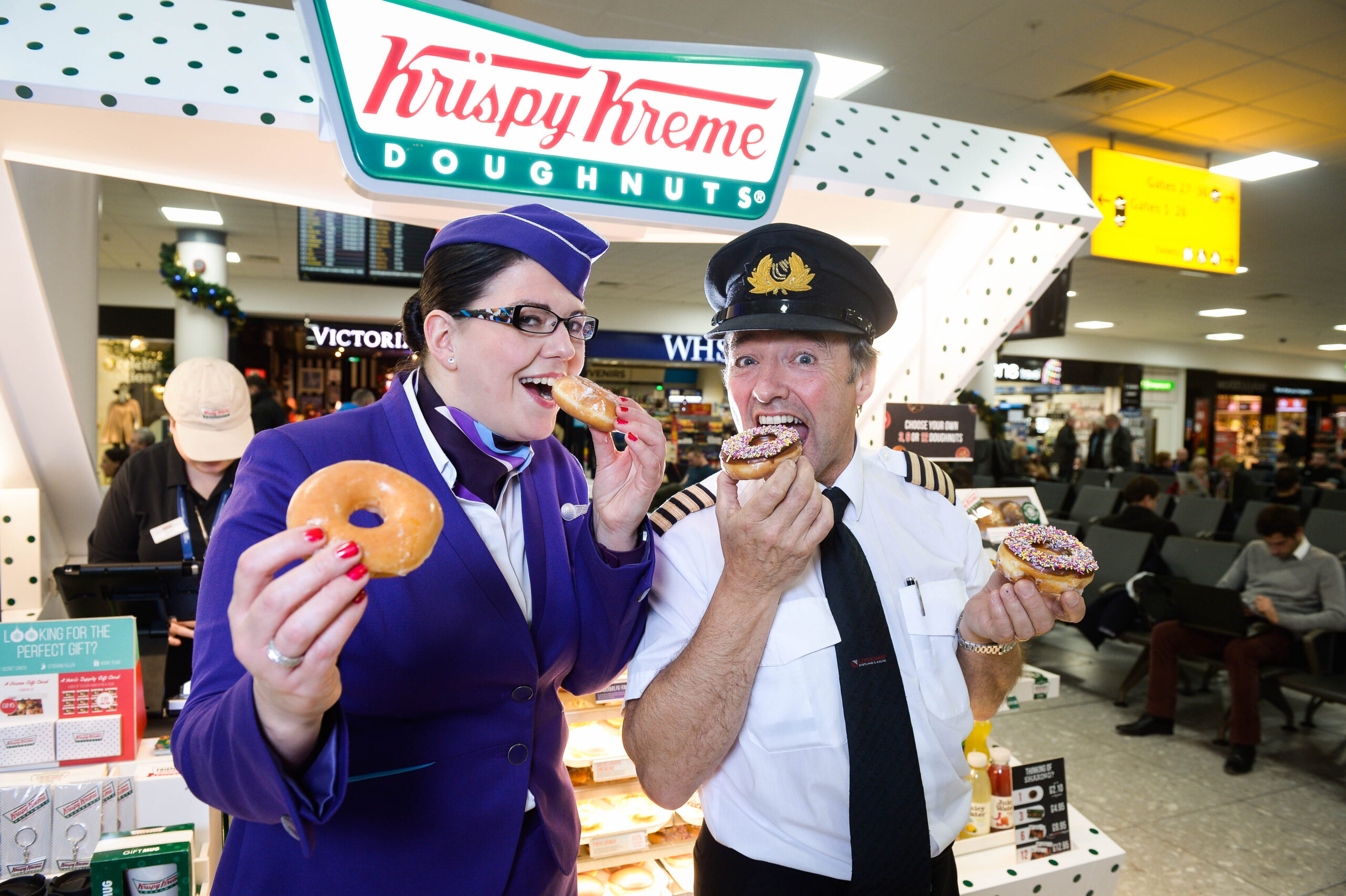 Picture by Nick Ponty 19/11/16 Krispy Kreme opens at Glasgow Airport Logan Air Cabin Crew manager Avril McEwan and Pilot Eddie Watt try out some doughnuts.